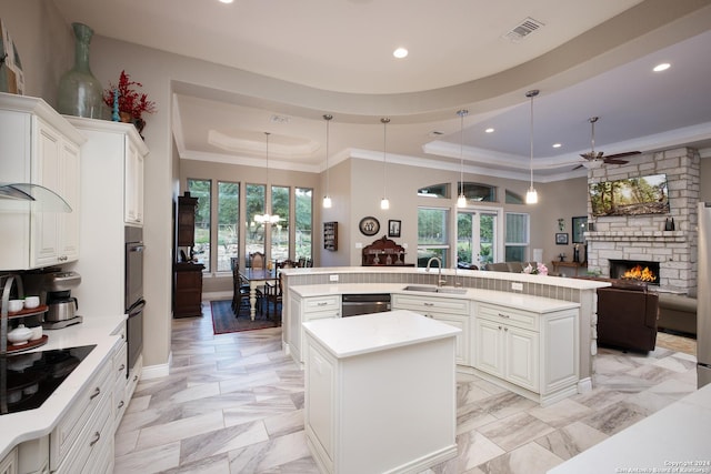 kitchen featuring ceiling fan, pendant lighting, a center island with sink, and black appliances