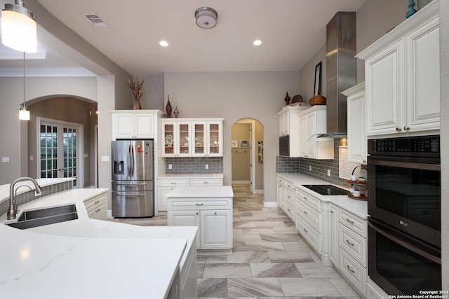 kitchen with backsplash, stainless steel refrigerator with ice dispenser, sink, white cabinetry, and hanging light fixtures