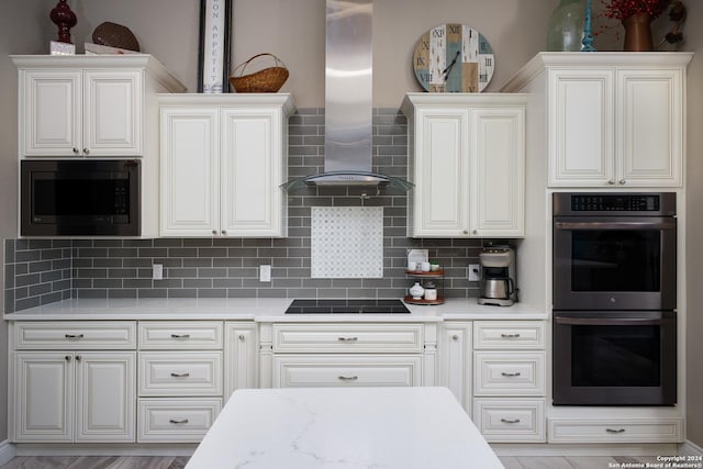 kitchen with wall chimney range hood, decorative backsplash, built in microwave, stainless steel double oven, and black electric cooktop