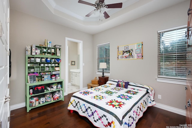 bedroom featuring ceiling fan, ensuite bathroom, dark hardwood / wood-style floors, and a raised ceiling