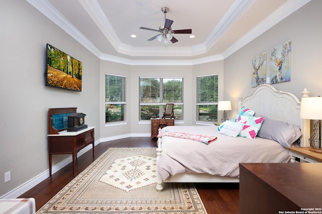 bedroom with ceiling fan, dark wood-type flooring, crown molding, and a raised ceiling