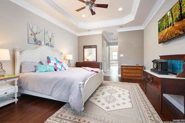 bedroom with dark hardwood / wood-style floors, ceiling fan, ornamental molding, and a raised ceiling