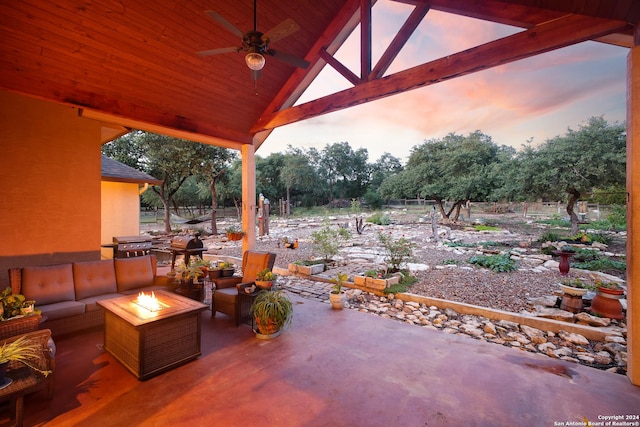 patio terrace at dusk featuring ceiling fan, an outdoor living space with a fire pit, and grilling area