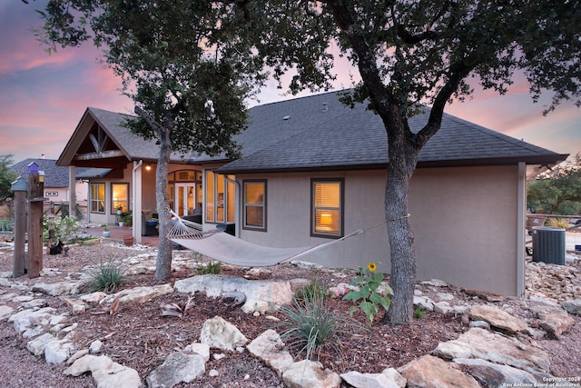 back house at dusk featuring central AC unit and a patio