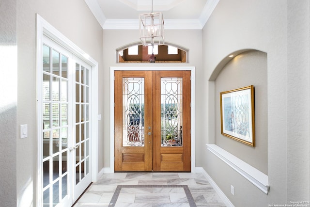 foyer entrance featuring crown molding, french doors, and an inviting chandelier