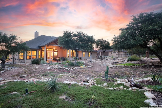 back house at dusk featuring a patio