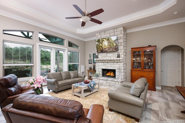 living room featuring ceiling fan, a fireplace, a raised ceiling, crown molding, and french doors