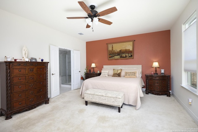 bedroom featuring connected bathroom, light colored carpet, and ceiling fan