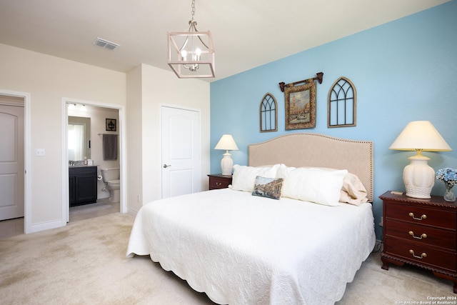 bedroom featuring light carpet, an inviting chandelier, and ensuite bath