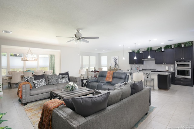 tiled living room with ceiling fan, a textured ceiling, and a wealth of natural light