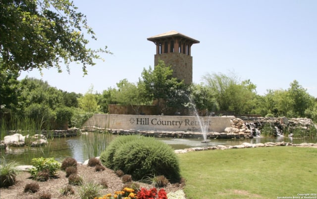 community sign featuring a water view and a lawn