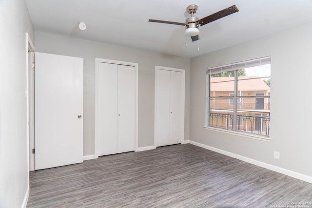 unfurnished bedroom with ceiling fan, hardwood / wood-style floors, and multiple closets