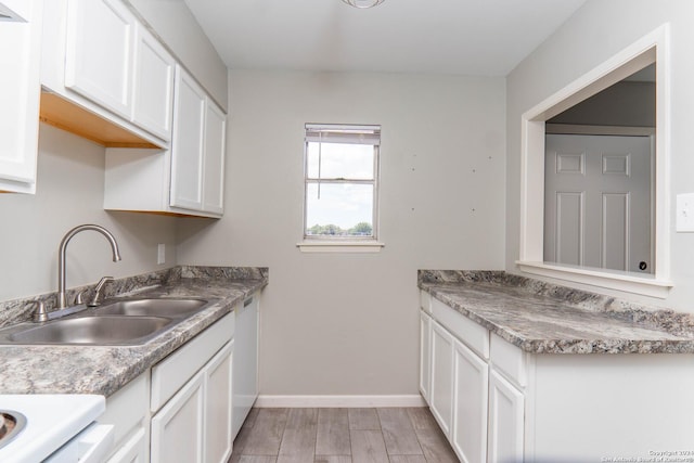 kitchen featuring dishwashing machine, sink, and white cabinetry