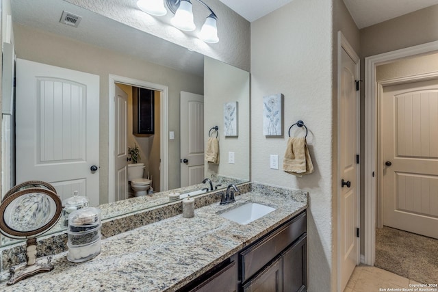 bathroom with toilet, tile patterned flooring, and vanity