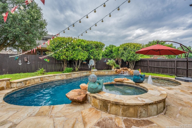 view of pool featuring an in ground hot tub, pool water feature, and a patio