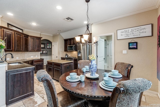 dining area with a chandelier, crown molding, and sink