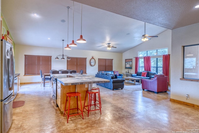 kitchen featuring stainless steel appliances, vaulted ceiling, a kitchen breakfast bar, a textured ceiling, and a center island