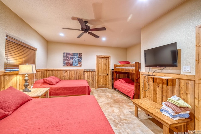 bedroom featuring ceiling fan, light colored carpet, wood walls, and a textured ceiling