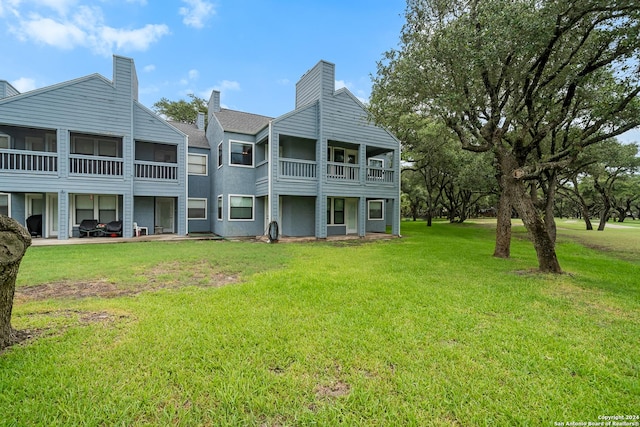 rear view of house with a balcony and a lawn