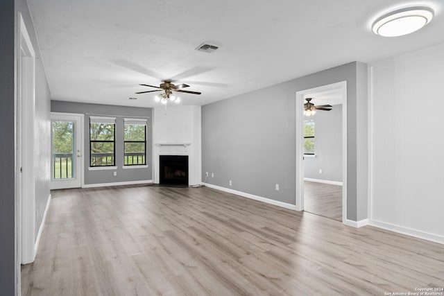 unfurnished living room featuring ceiling fan, a fireplace, and light hardwood / wood-style flooring