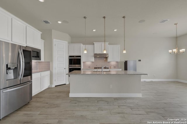 kitchen with white cabinets, hanging light fixtures, an island with sink, and appliances with stainless steel finishes