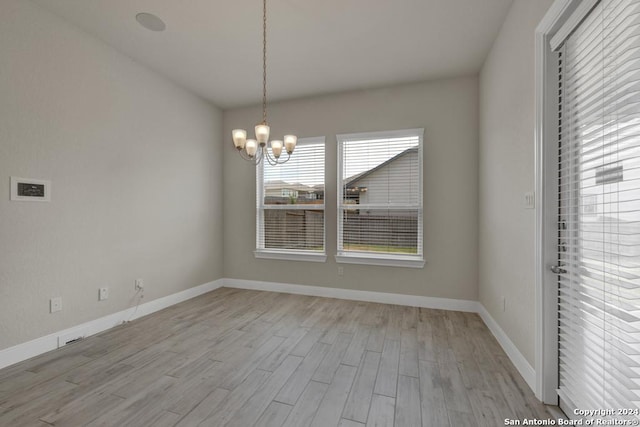 unfurnished dining area featuring light wood-type flooring and a notable chandelier