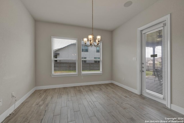 unfurnished dining area with light wood-type flooring and a chandelier