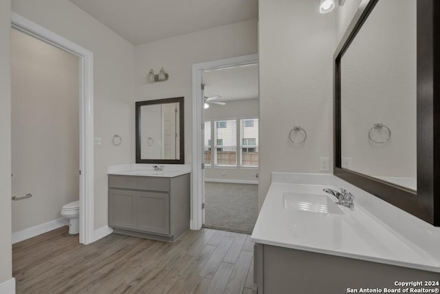 bathroom featuring toilet, vanity, hardwood / wood-style floors, and ceiling fan