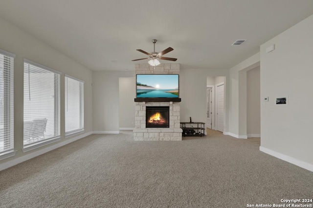 unfurnished living room featuring ceiling fan, light carpet, and a stone fireplace