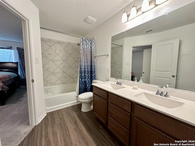 full bathroom featuring toilet, hardwood / wood-style floors, shower / tub combo, a textured ceiling, and vanity