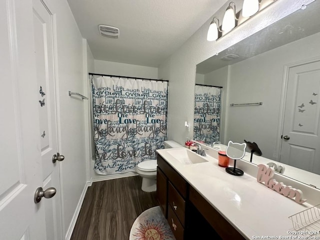 full bathroom featuring hardwood / wood-style floors, a textured ceiling, vanity, shower / bath combination with curtain, and toilet