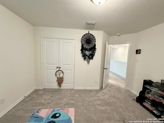 interior space with a textured ceiling and light colored carpet