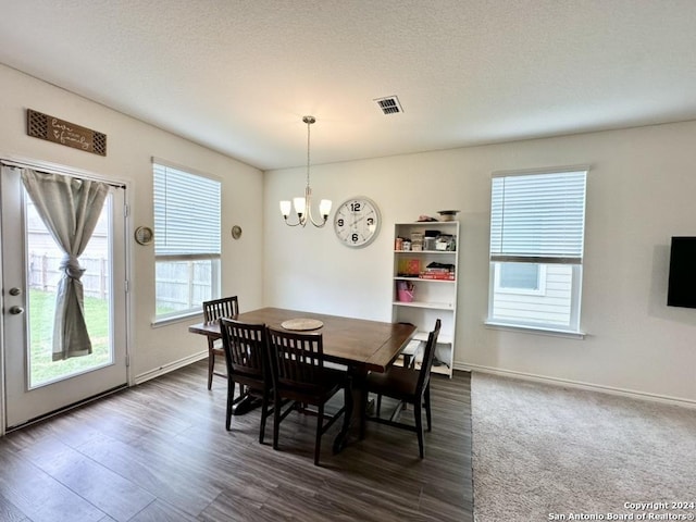 dining room featuring a textured ceiling, dark hardwood / wood-style flooring, and a chandelier