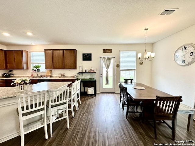 dining area with a textured ceiling, dark hardwood / wood-style flooring, and a chandelier