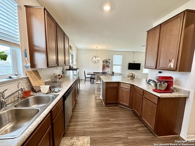 kitchen featuring decorative light fixtures, stainless steel dishwasher, kitchen peninsula, sink, and dark wood-type flooring