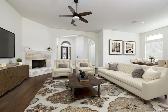 living room featuring a fireplace, a textured ceiling, hardwood / wood-style flooring, and ceiling fan