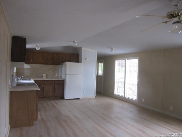 kitchen featuring lofted ceiling, light wood-style floors, open floor plan, light countertops, and freestanding refrigerator