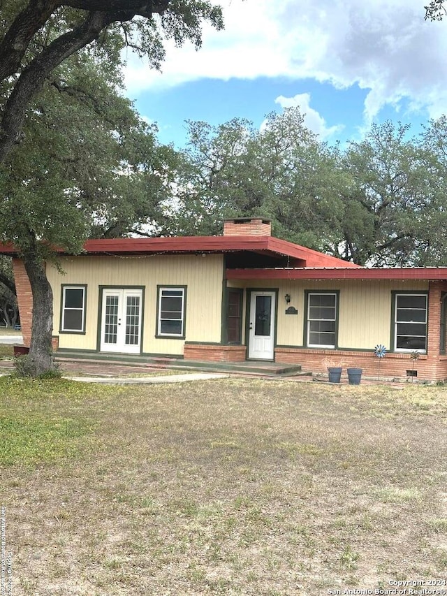 ranch-style home featuring french doors, a chimney, and a front yard