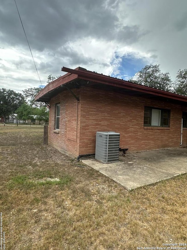 view of side of home featuring a yard, central AC unit, and a patio