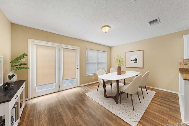 dining space with a textured ceiling, a healthy amount of sunlight, and wood-type flooring