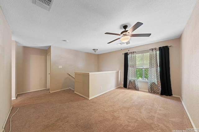 spare room with a textured ceiling, ceiling fan, and light colored carpet