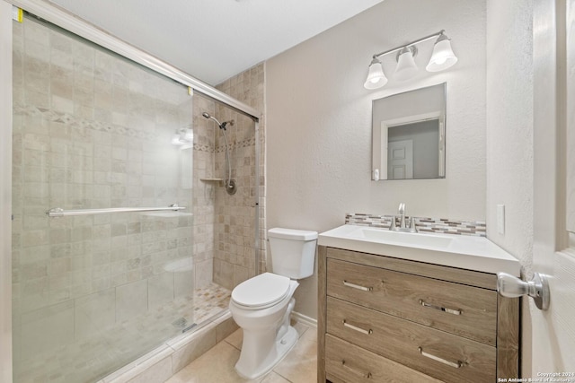 bathroom with toilet, a shower with door, vanity, and tile patterned flooring