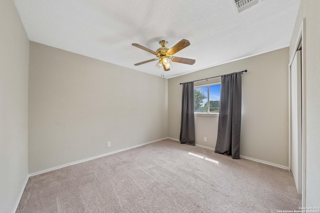 spare room with light carpet, ceiling fan, and a textured ceiling