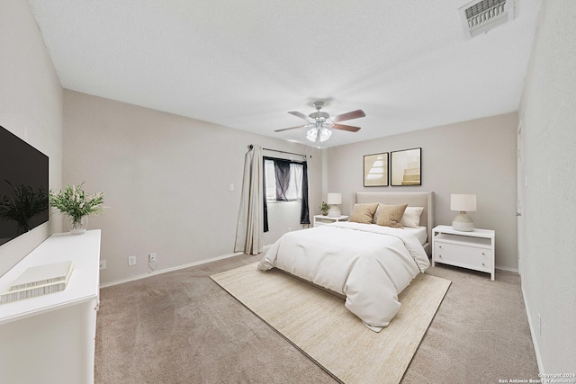 carpeted bedroom with ceiling fan and a textured ceiling