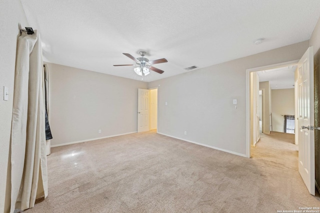 unfurnished room with light carpet, ceiling fan, and a textured ceiling