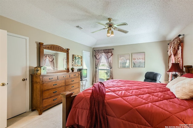 bedroom with a ceiling fan, light colored carpet, visible vents, and a textured ceiling