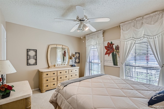 bedroom featuring light carpet, ceiling fan, and a textured ceiling