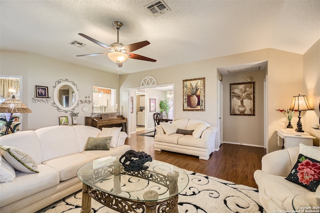 living room with a ceiling fan, visible vents, dark wood finished floors, and a textured ceiling