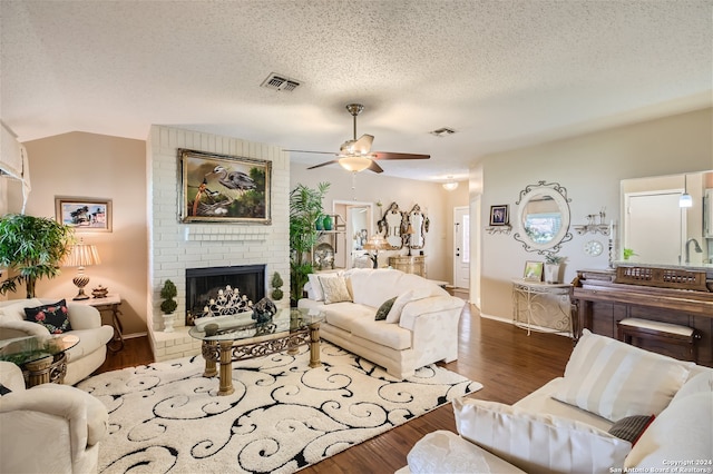 living area with a fireplace, visible vents, dark wood-type flooring, vaulted ceiling, and a textured ceiling