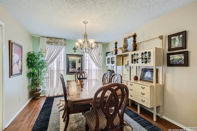 dining area with dark wood-style floors, a notable chandelier, and a textured ceiling